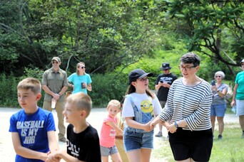 Guests in pairs of two hold hands and participate in a Wampanoag dance on the Historic Patuxet Homesite.