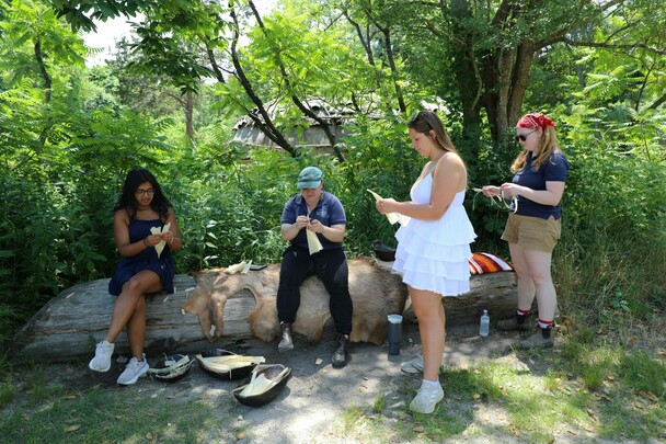 Museum educators instruct guests on how to make a corn husk doll on the Homesite.