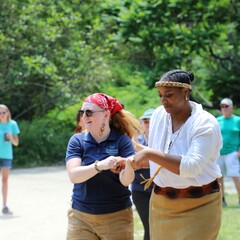 Two Educators on the Historic Patuxet Homesite hold hands and demonstrate a Wampanoag dance