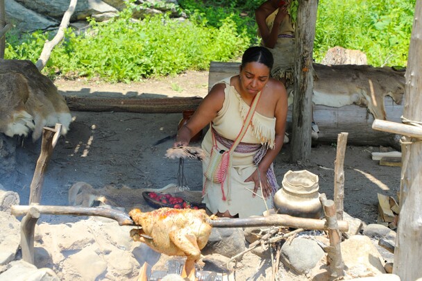 Museum Educator tends to roasting turkey at the Cooking Arbor