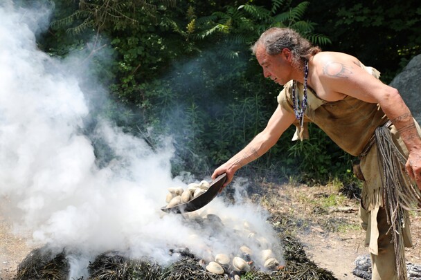 Indigenous Educator tosses bowl of quahogs onto burning clambake