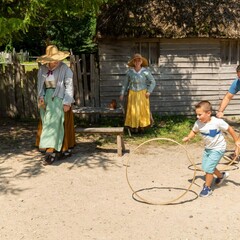 Father and son spin hoops with Pilgrims in English Village