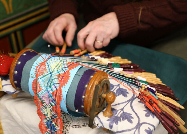 An artisan at the Winter Fine Arts & Craft Fair demonstrates how to make intricate lace patterns using bobbins.