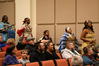 Members of Wetu Ways enter the theater in front of seated guests