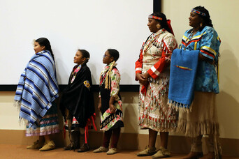 Members of Wetu Ways stand on stage waiting to demonstrate the Blanket Dance.
