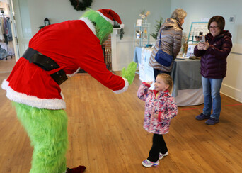 The Grinch high-fives a young guest at the Winter Fine Arts & Craft Fair.